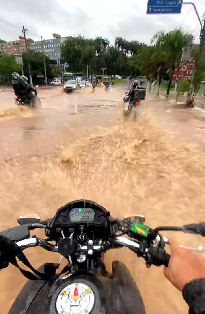 Entregador atravessando alagamento na Baixada Santista